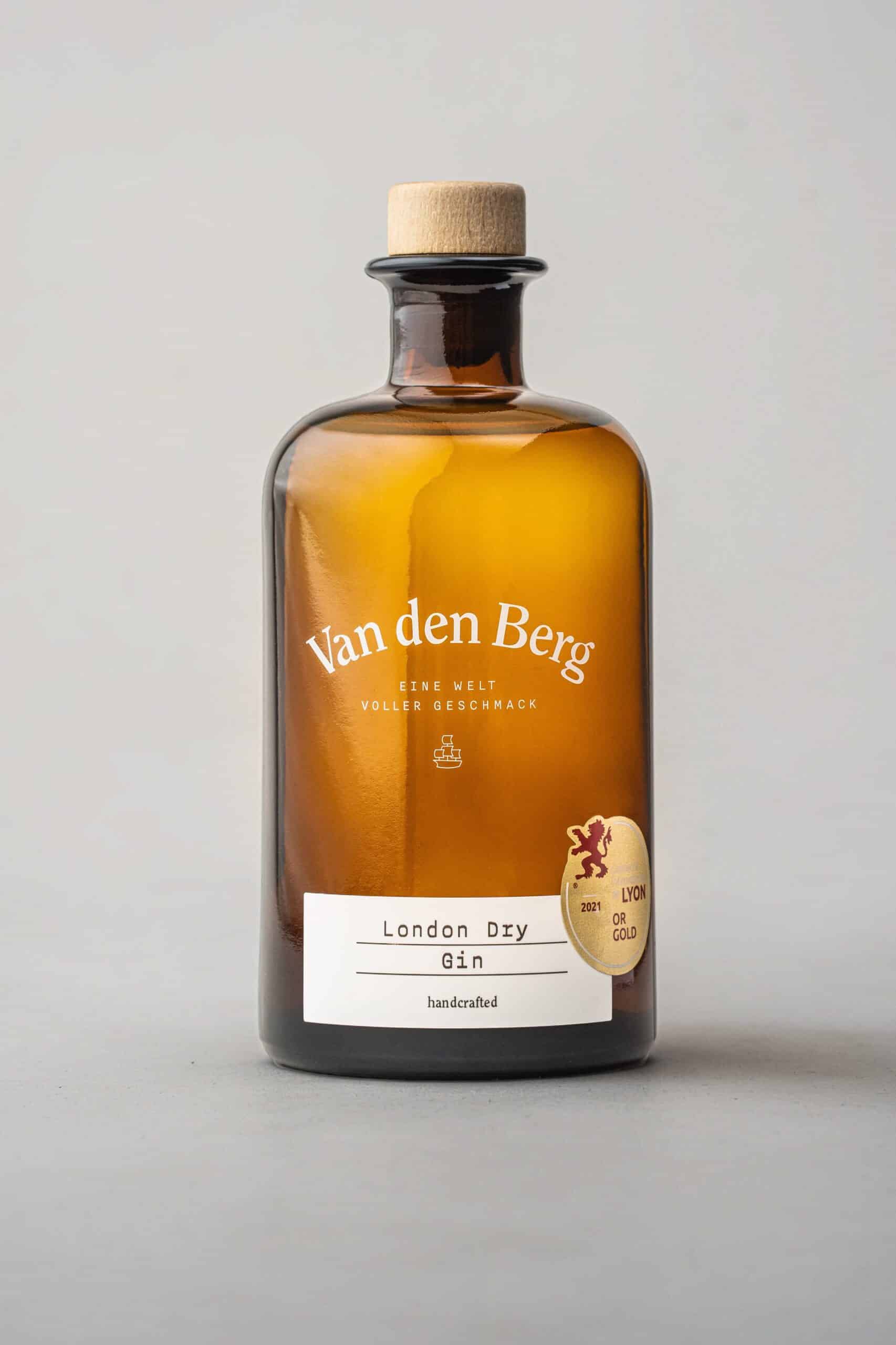 Eine braune Glasflasche mit Korken, die schön als Van den Berg | London Dry Gin beschriftet ist, trägt einen Goldmedaillenaufkleber von Lyon Gold 2021. Die Flasche wird vor einem neutralen Hintergrund präsentiert, was ihre vornehme Präsenz unterstreicht.