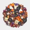 Eine Auswahl farbenfroher Trockenfrüchte und Blumen, darunter Blaubeeren der Marke Björn Blaubeer, Ananaswürfel, Orangenschalen und violette Blütenblätter, angeordnet in einem kreisförmigen Muster auf weißem Hintergrund.