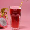 Auf einem rosa Hintergrund steht ein Glas mit rotem Eistee IDA ROSE. Auf dem Glas befindet sich ein gelb gestreifter Strohhalm und das Wort „Loftea“. Daneben sorgen eine halbe Drachenfrucht und ein Teil eines Palmblatts für eine exotische Note.