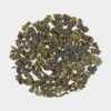 Eine runde Präsentation von losem Milky Oolong-Tee zeigt dunkelgrüne und braune gekräuselte Blätter, die vor einem schlichten weißen Hintergrund ein subtiles Milcharoma verströmen.